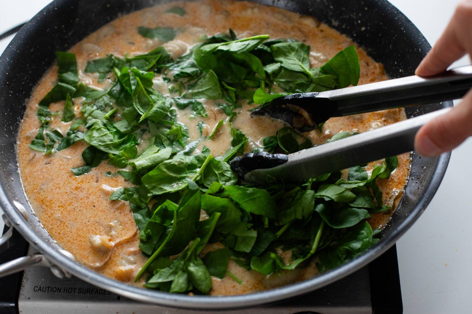 Adding spinach to skillet.
